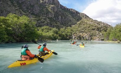 Kayak sobre río con fondo de montañas y bosque